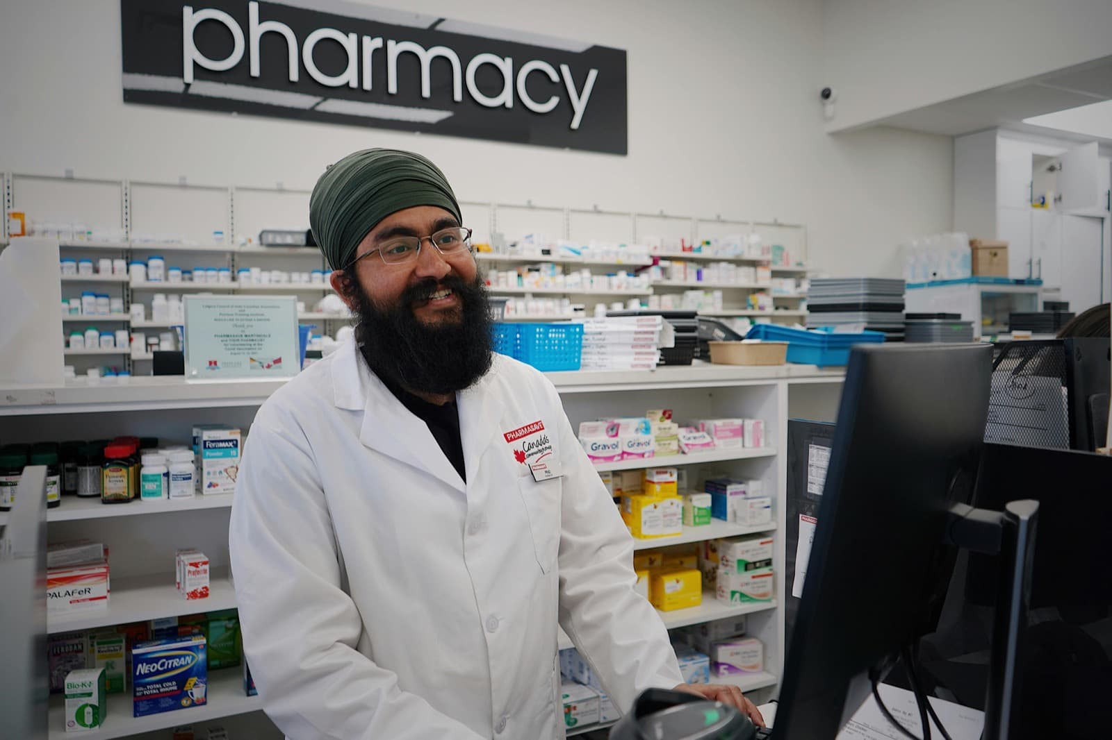 Pharmacist working at the counter with a patient.
